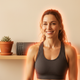 Headshot of a smiling, fit woman in her 30s with subtle orange heat-effect accents, against a light beige background.